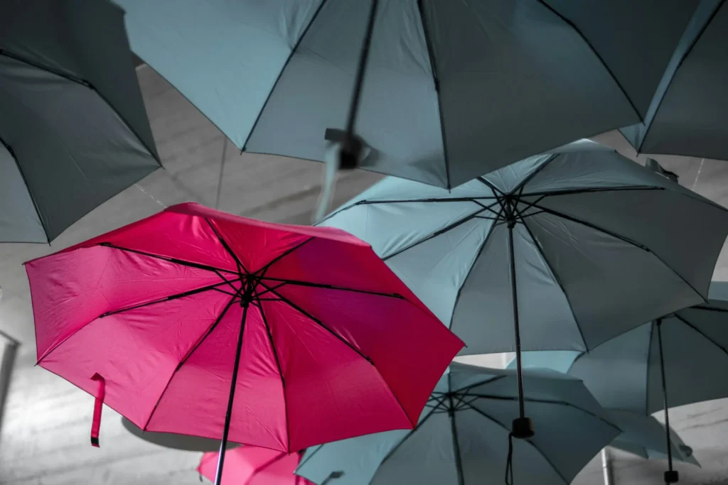 Illustration de la stratégie de différenciation en marketing : un parapluie rose se distingue parmi des parapluies noirs